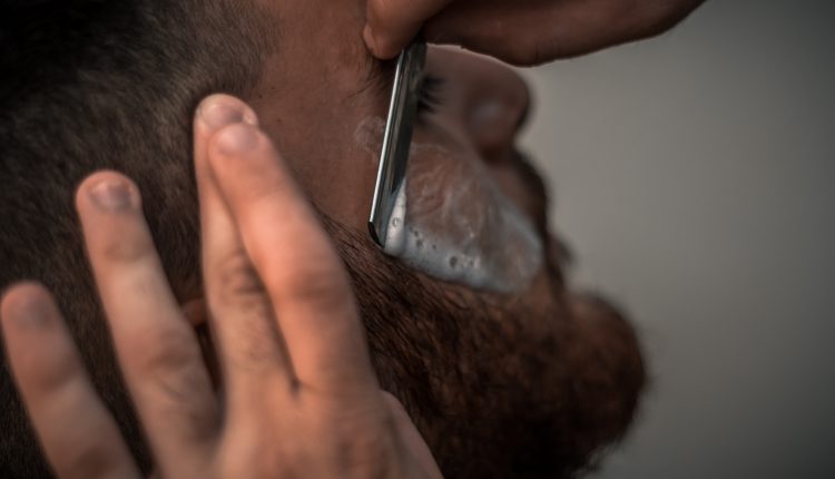 גבר מזוקן שמישהו אחר מגלח לו את הזקן